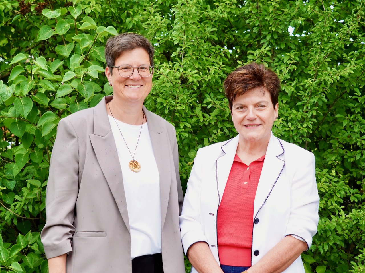 Zwei Frauen vor einer grünen Hecke, Schulleiterin und Sekretärin der GS Stallwang